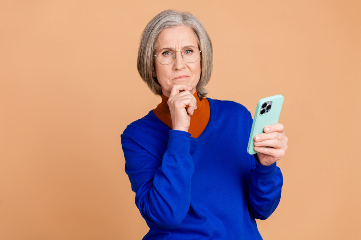 Medicare scams, open enrollment, older woman thinking while holding phone