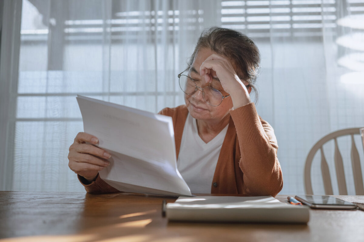 Medi-Cal asset limit, senior Asian woman looks stressed when she looking at notice of costs
